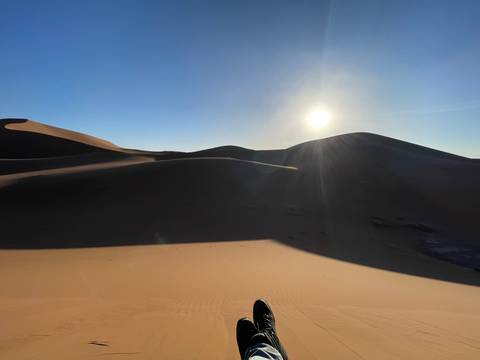       Sand dunes at sunset with the sun on the horizon.
  