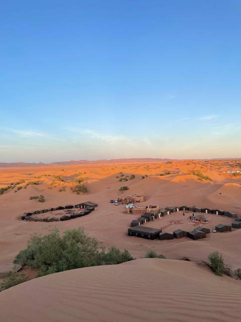 Desert camp with tents and vehicles in the sand dunes.