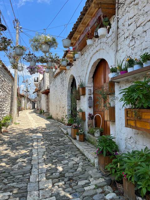 Charming cobblestone street with flower-adorned houses.
