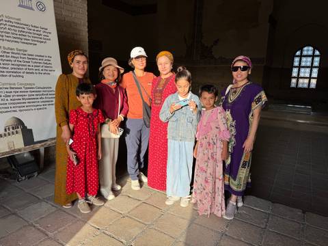 Group of people inside a building with traditional designs on the walls.
