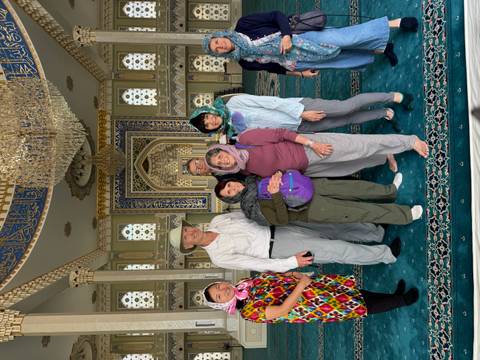 Group of people in a lavishly decorated hall with traditional Islamic architecture.