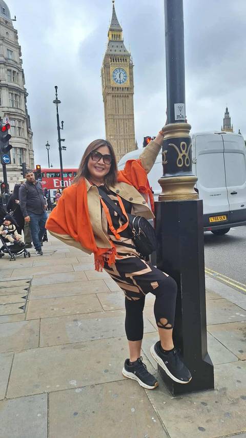 Woman posing on a city street with a double-decker bus.