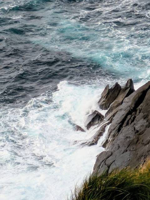       Waves crashing against jagged rocks on a seaside coast.
  