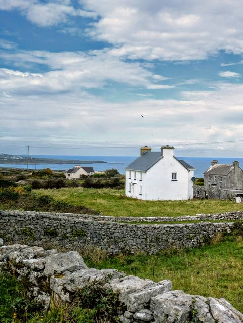       Coastal landscape with stone walls and white houses.
  