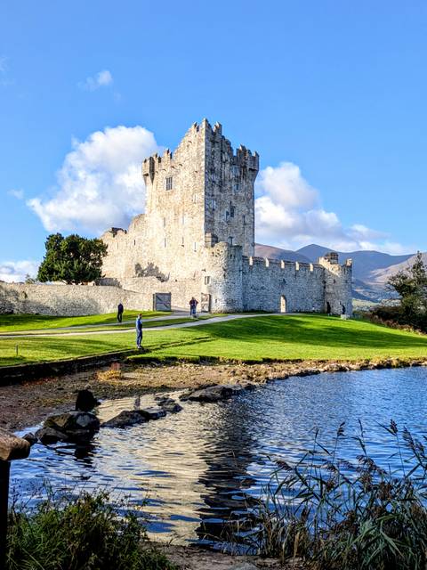       Historic stone castle with lush landscape under a blue sky.
  