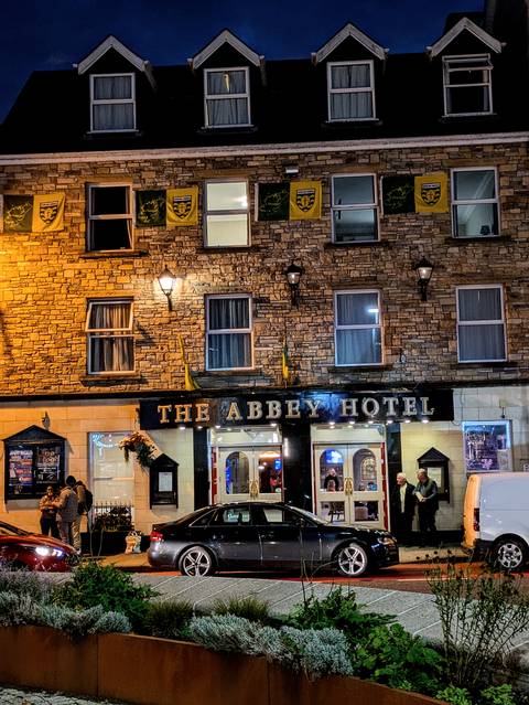       The front of The Abbey Hotel with people outside.
  