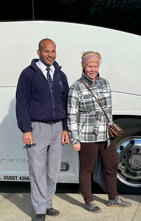 Couple posing in front of a bus wearing winter clothing.