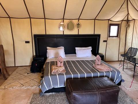       Interior of a cozy tent with a neatly arranged bed and towels.
  