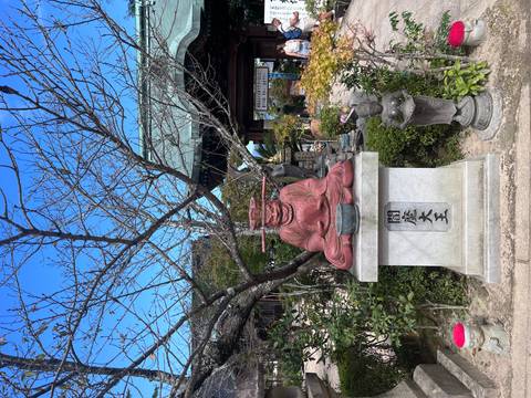 Red deity statue in a temple garden.