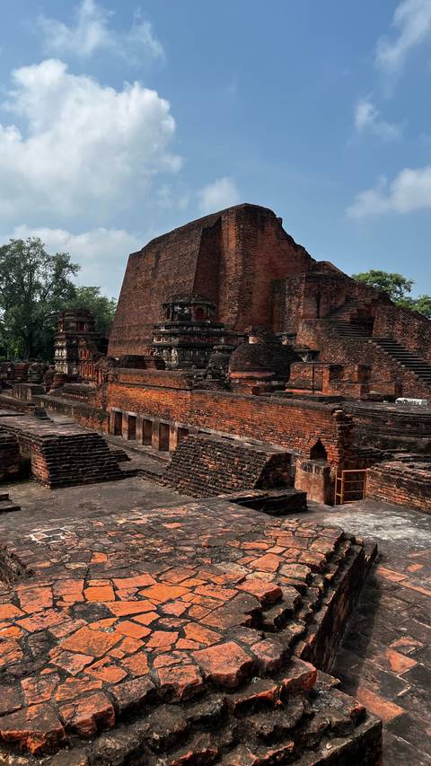 Ancient brick structures and ruins against a backdrop of trees.
