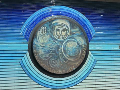       Circular mural of an astronaut with Russian text in a blue-tiled setting.
  