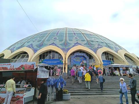      Large domed market building with a crowd of people entering.
  