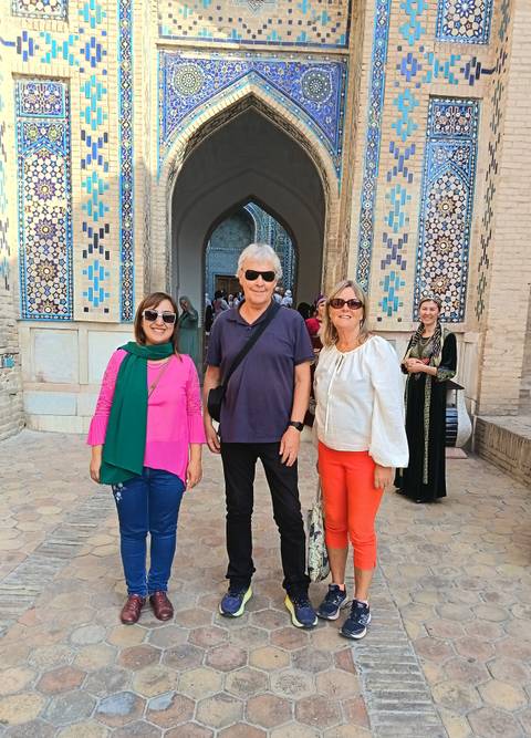       Three people posing in front of a historic building with tile patterns.
  