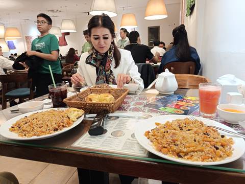 Woman dining in a restaurant with plates of traditional food.