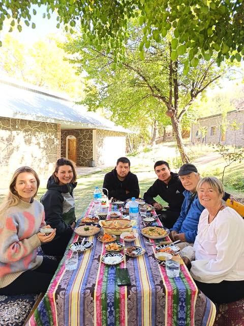       Group of people enjoying a meal outdoors around a table.
  