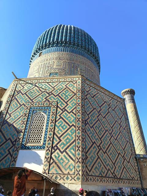 Close-up of an ornately tiled tower under a blue sky.