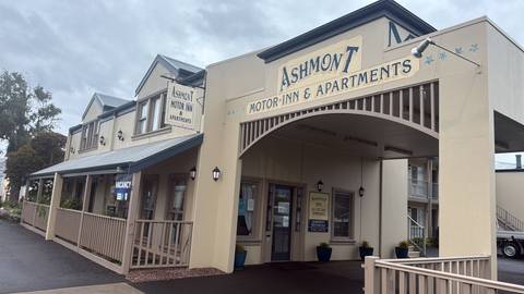       A motor inn with signs and a parking area.
  