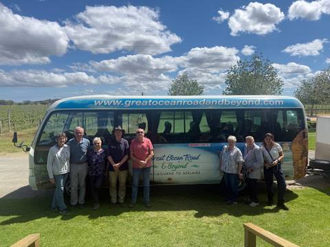       Group of people posing in front of a tour bus.
  