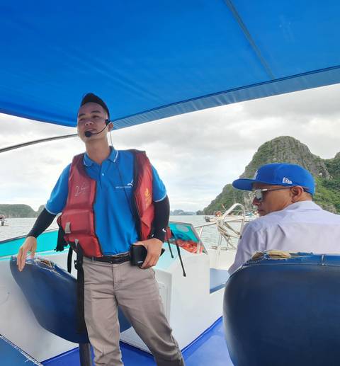 People on a boat tour with a scenic mountainous backdrop.