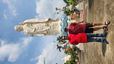 Two men posing in front of a large white Buddha statue.