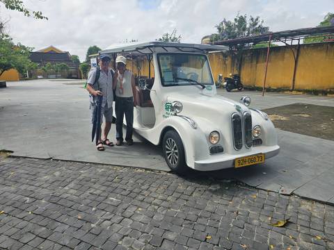 Two men standing beside a unique-looking electric cart.