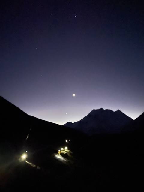 Night sky with mountains silhouetted and visible stars.