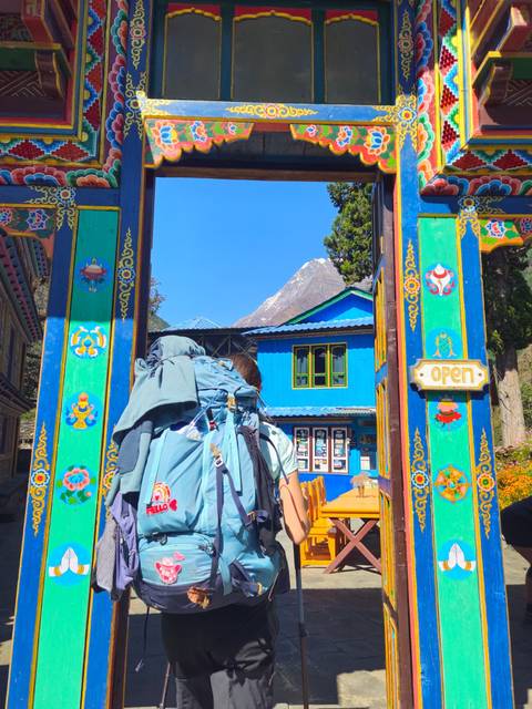 A hiker with a backpack walking through a colorful gate with a mountain in the background.