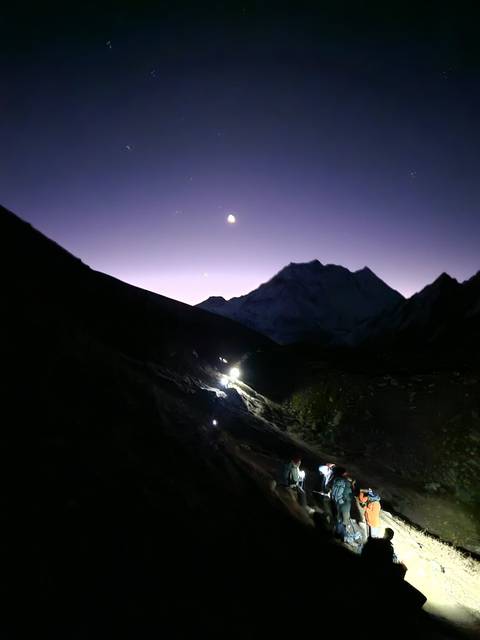 Mountain silhouette under a night sky with moon.