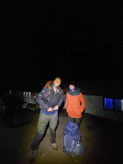 Two people outdoors smiling at night.