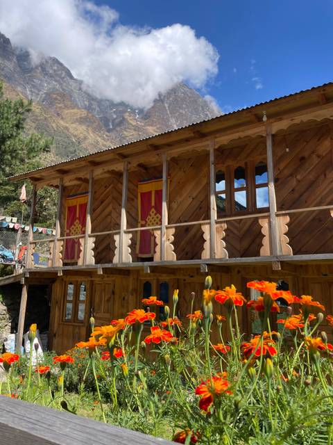      Wooden traditional house with flowers in the foreground.
  
