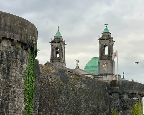 Cathedral towers with green domes and a clock in the foreground.