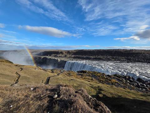 Dettifoss waterfall with rainbow and rugged landscape in Iceland.