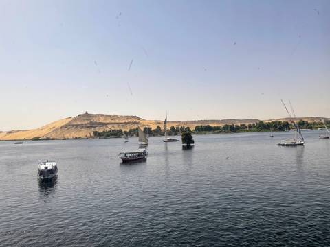       Several boats on a river with sandy hills in the background.
  