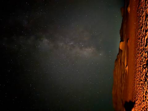 Star-filled night sky over desert dunes.