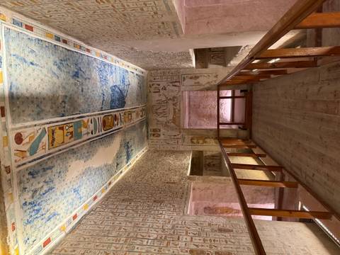       Decorated tomb with wall paintings and wooden pathway.
  