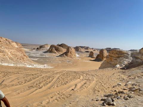       Sandy desert vista with rocky formations.
  