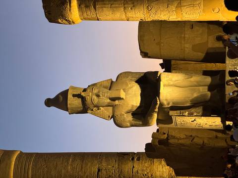       Large stone statue of a pharaoh with tourists around.
  
