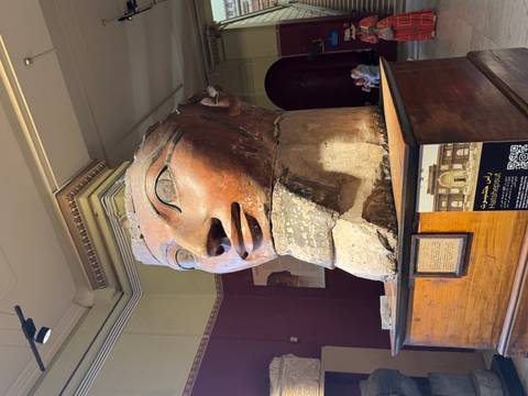       Ancient Egyptian sculpture with hieroglyphs and people in museum.
  