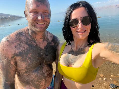       Couple covered in mud at the shore of the Dead Sea.
  