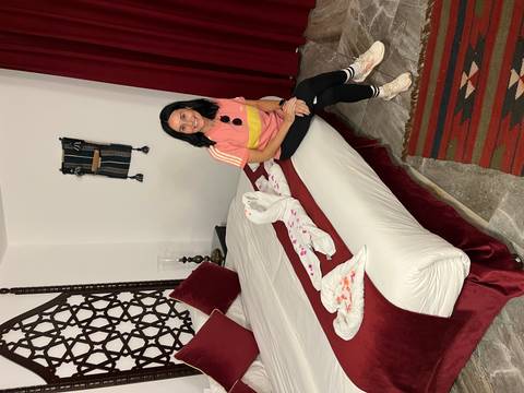 Woman sitting on a decorated bed in a hotel room.