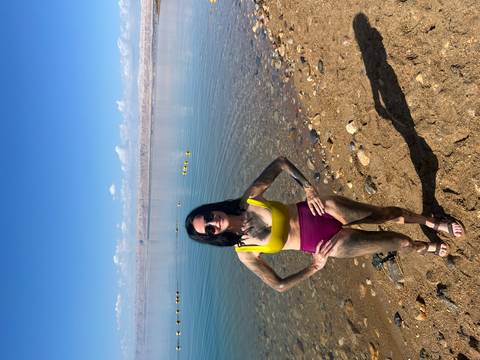 Woman standing on the shore of the Dead Sea with mud on her skin.