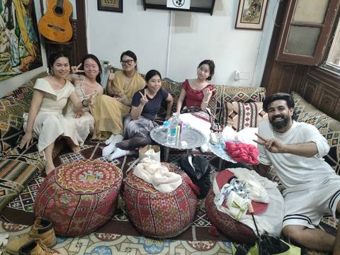 Group of people seated indoors on a variety of cushions.