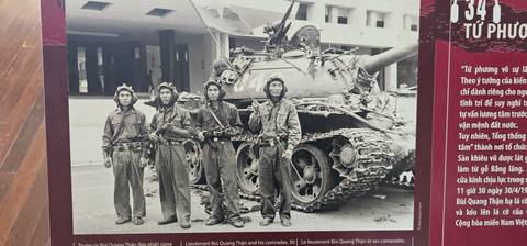       A historical photograph of soldiers in front of a tank.
  