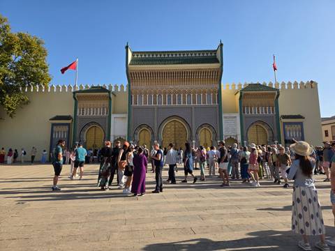 Group of tourists gathered outside a grand building.