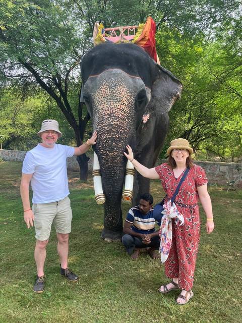 Couple interacting with an elephant in a natural setting.