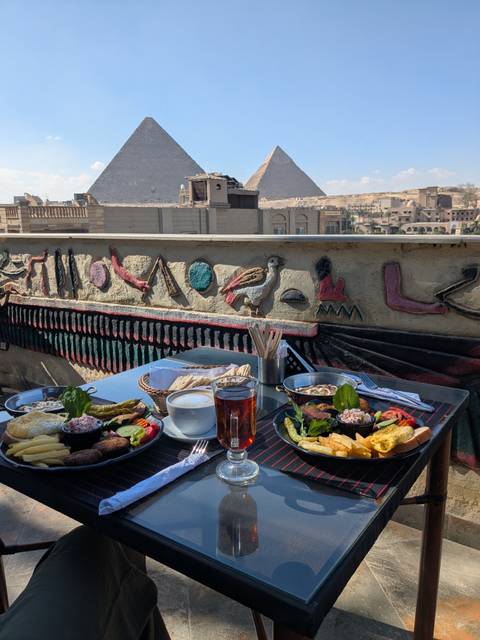 Plate of food and drink next to a wall with Egyptian hieroglyphs.