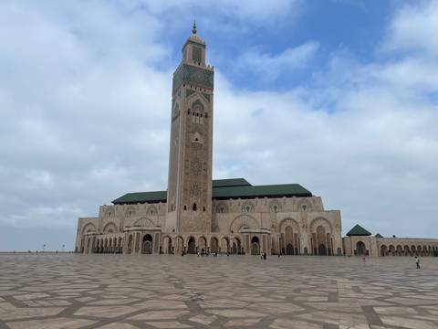 Grand mosque with a tall minaret against a partly cloudy sky.