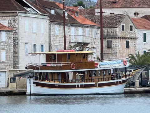       Wooden boat docked in front of stone buildings.
  