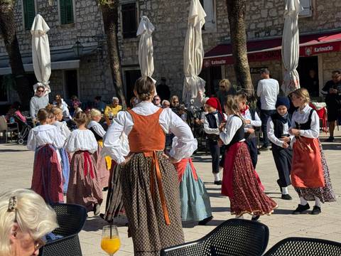 Children in traditional dress dancing in a public square.