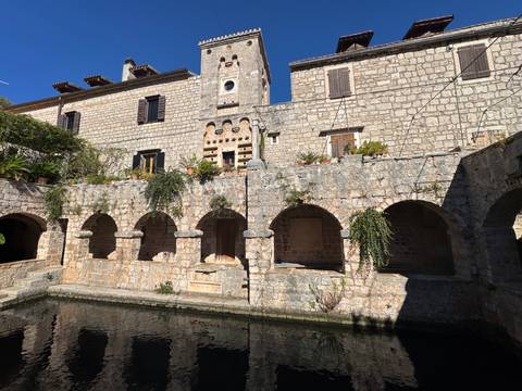       Rustic stone building with arched openings and plants.
  
